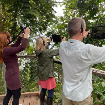 People holding screens up towards the Rainforest Biome at the Eden Project to reveal an augmented reality experience on the screen